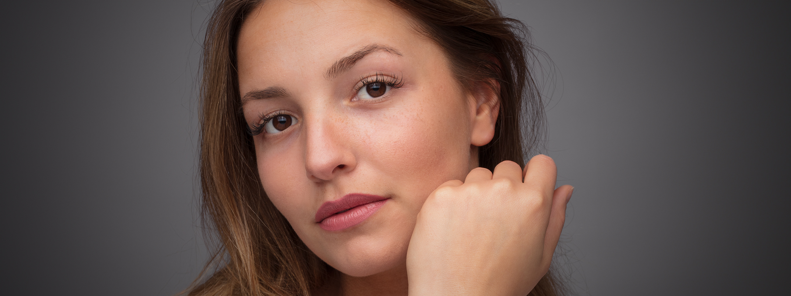 Portraitfoto einer jungen Frau mit der Hand am Kinn